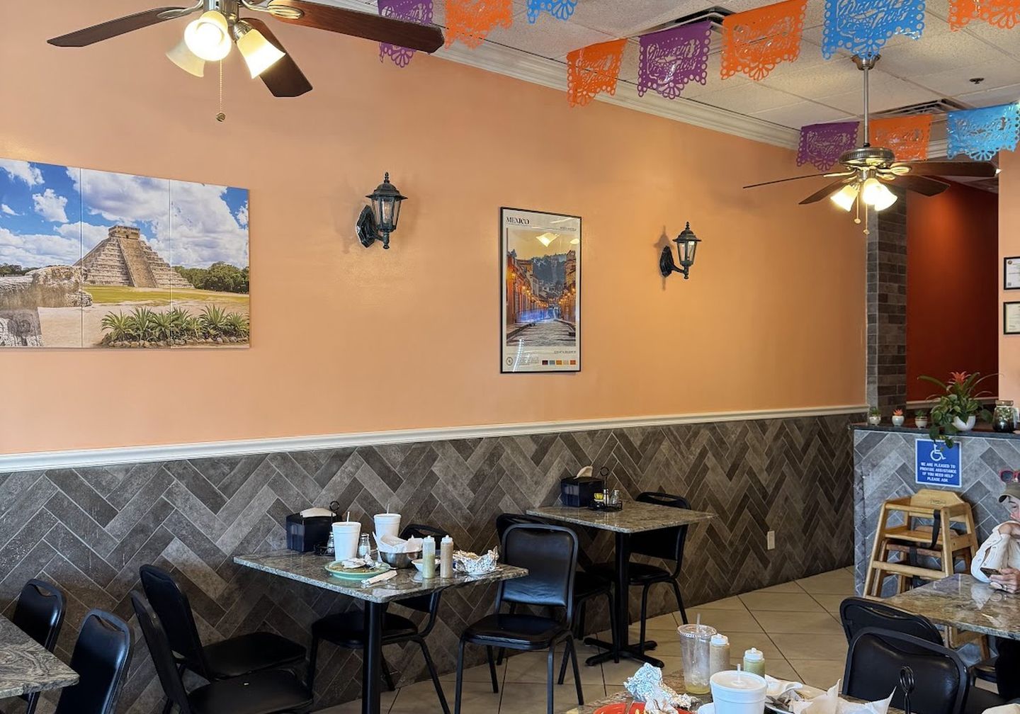 The festive dining room — terracotta walls, papel-picado banners and a desert mural