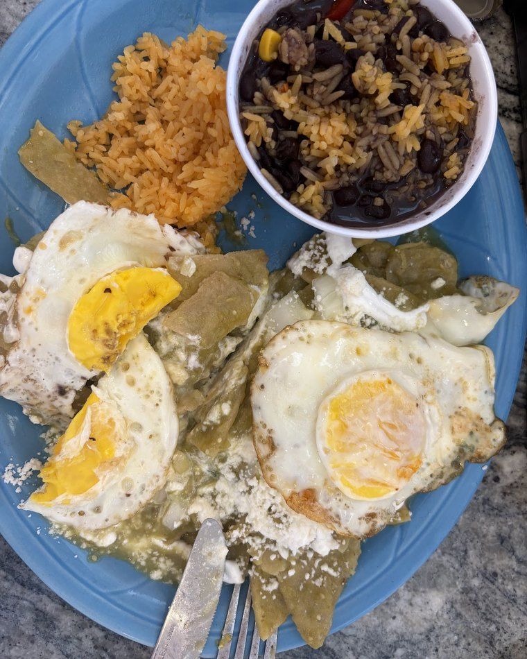 Breakfast plate — two fried eggs over green chilaquiles with rice and refried beans