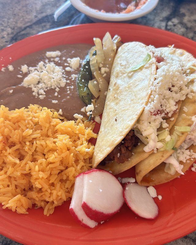 A combo plate with a soft taco, yellow rice and refried beans