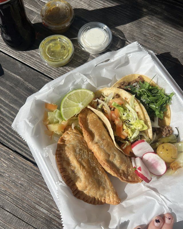 Two golden puffy tacos with lime and salsas
