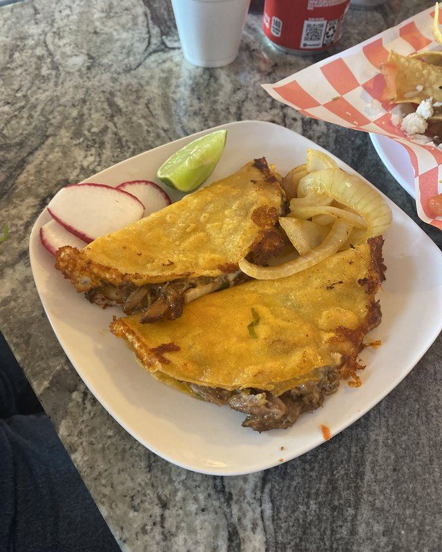 Two crisp golden fried tacos with radish and lime