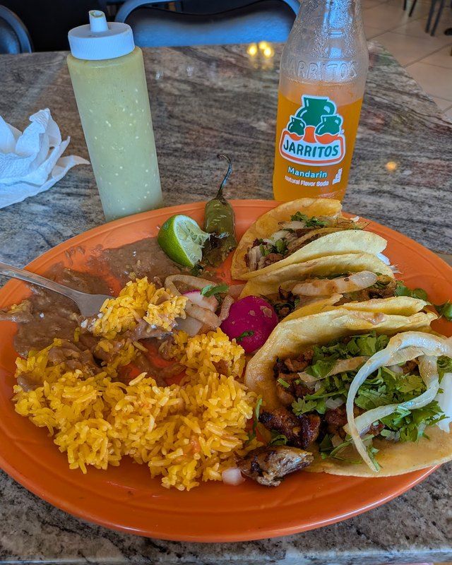 A combo plate with tacos, rice and a Jarritos soda outdoors