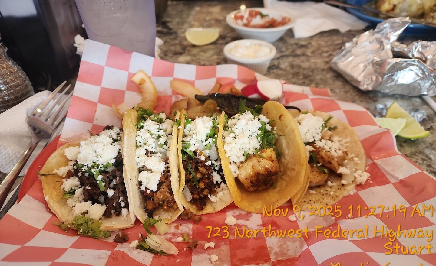 A basket of fresh street tacos on soft corn tortillas, topped with cilantro and onion, with lime on the side