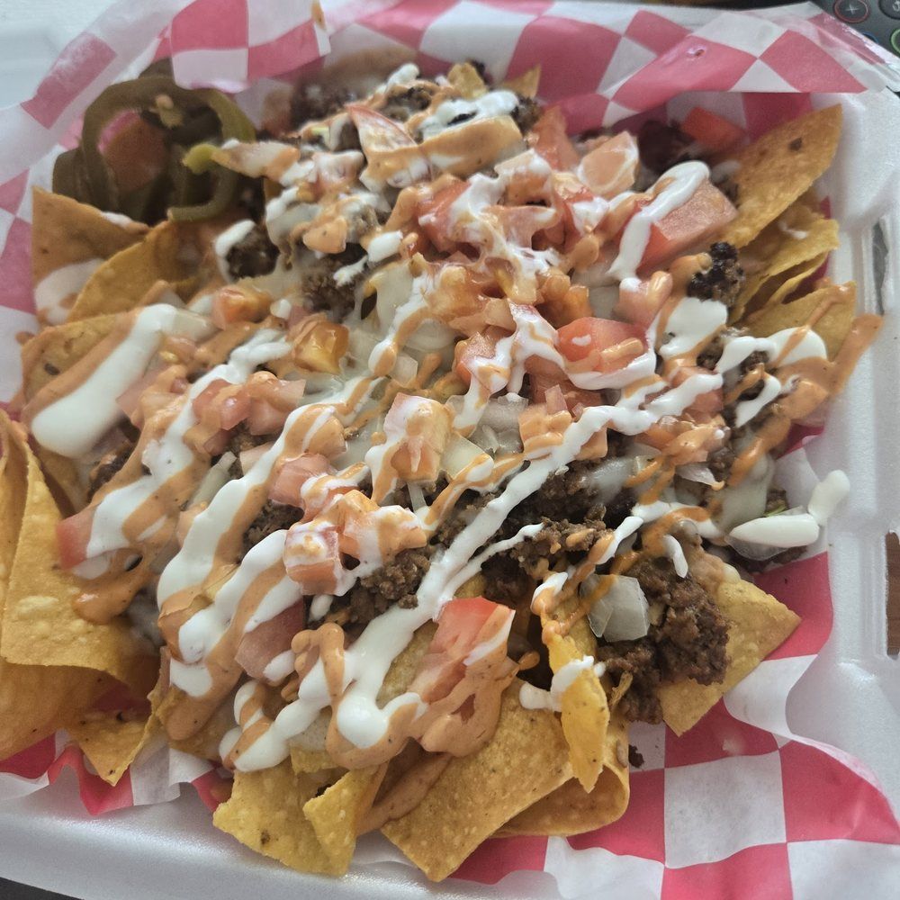 Loaded nachos — tortilla chips piled with meat, beans, pico and a crema-and-salsa drizzle in a basket