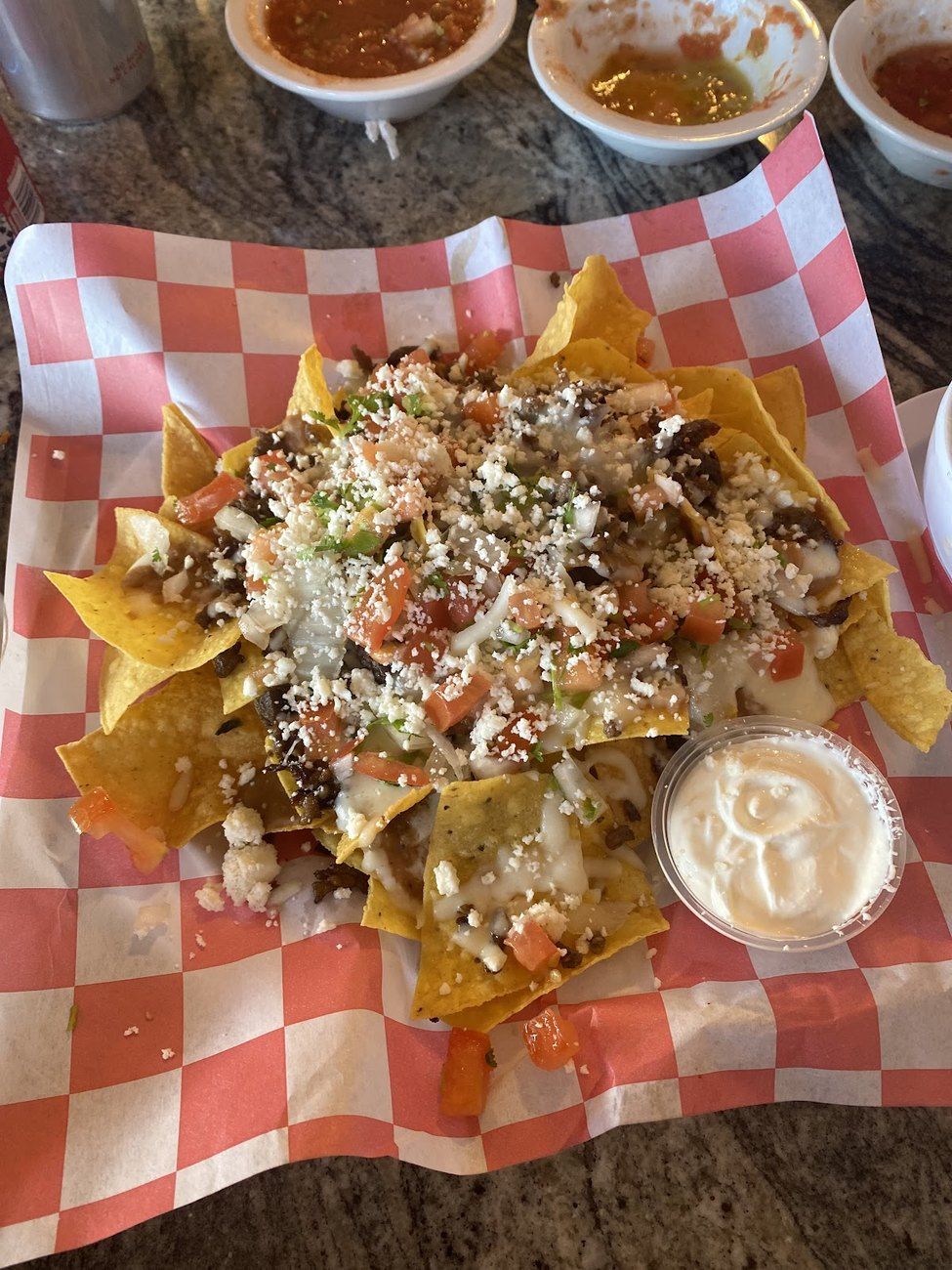 Loaded nachos topped with queso fresco and pico in a checkered basket