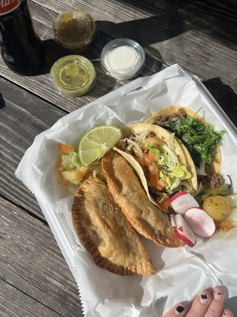 Two golden puffy tacos with lime and salsas