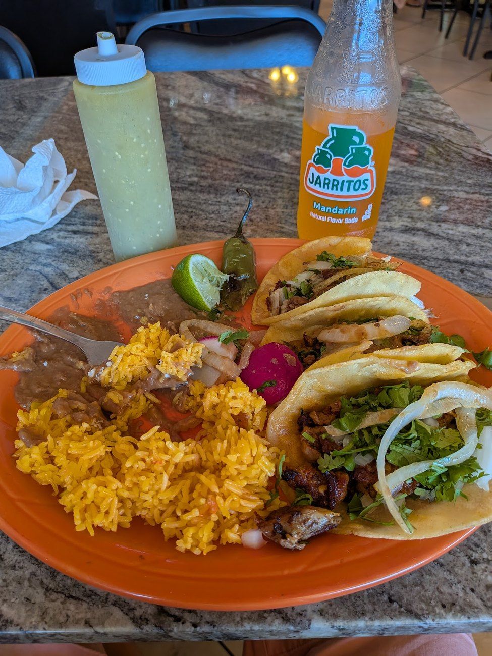 A combo plate with tacos, rice and a Jarritos soda outdoors
